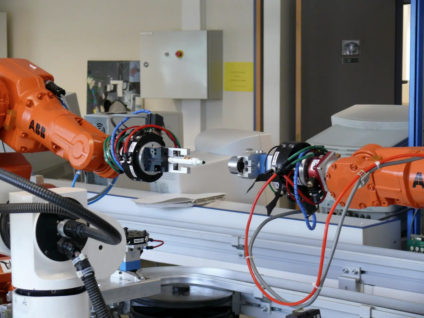 Lineer transfer ekseninin yanında pnömatik tutuculu turuncu robotlar