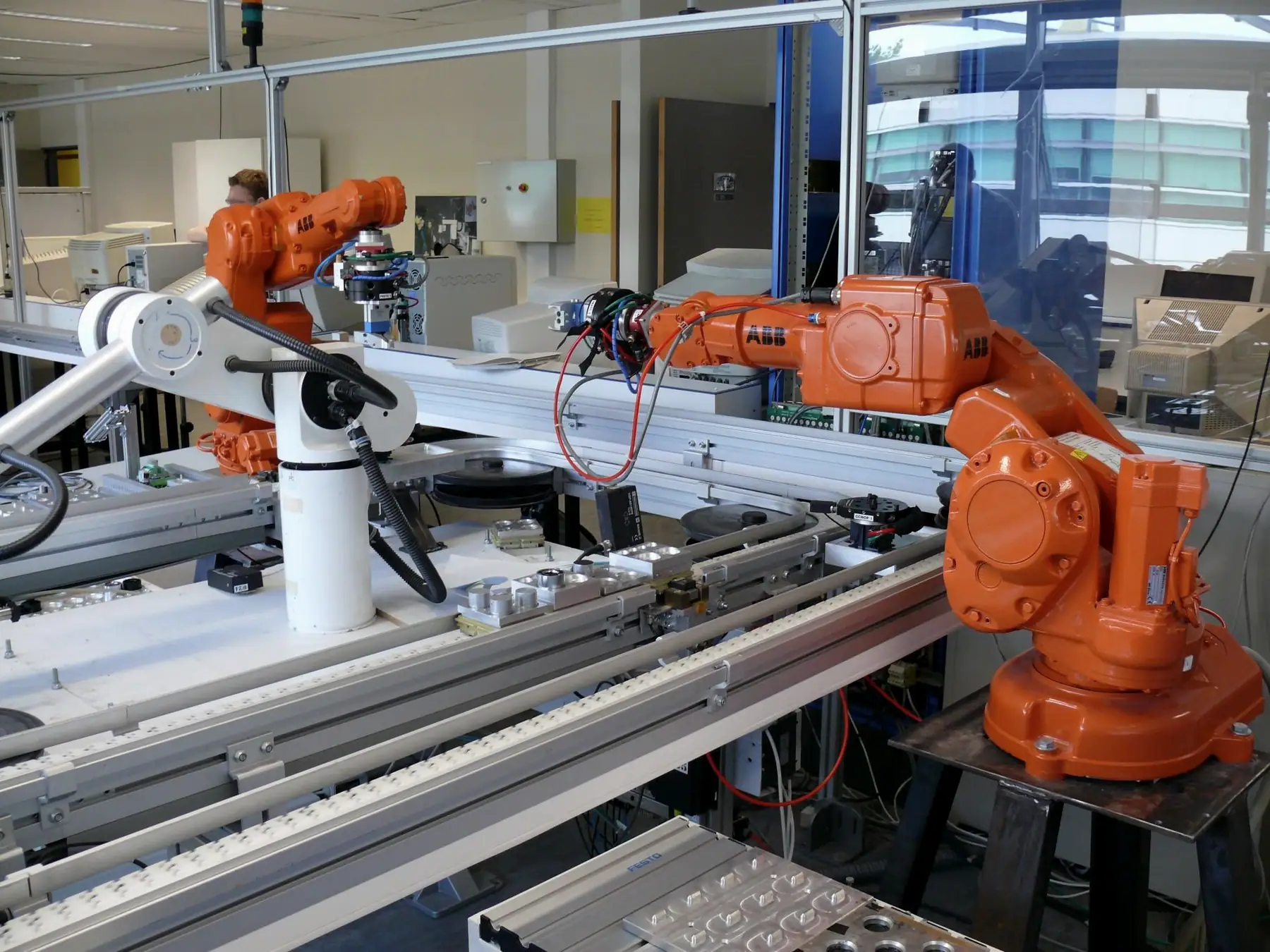 Transfer hattı üzerinde çalışan iki turuncu robot ve taşıma modülü