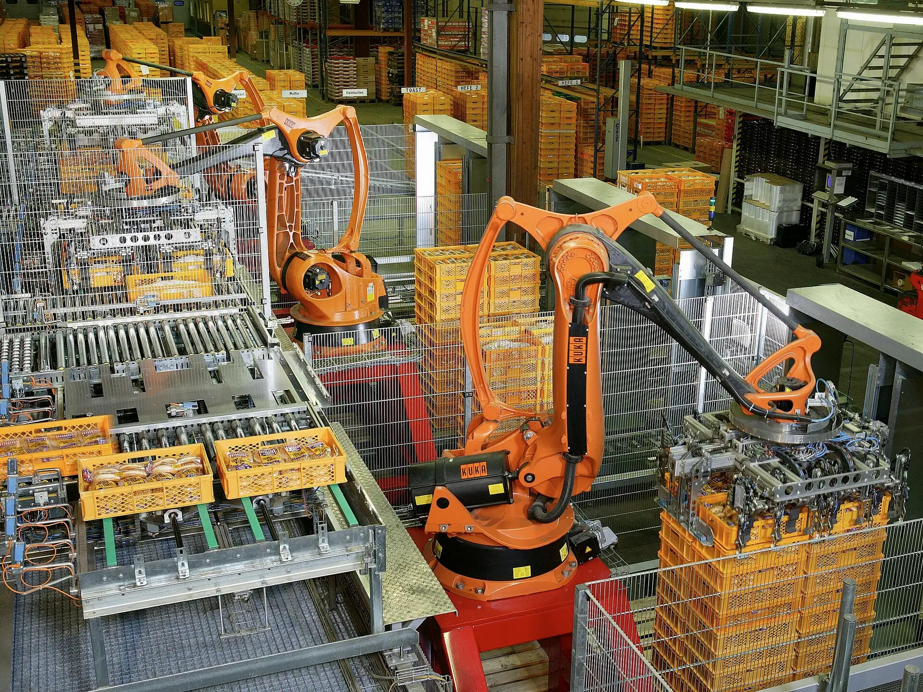 Turuncu robotların kasaları paletlediği paketleme alanı
