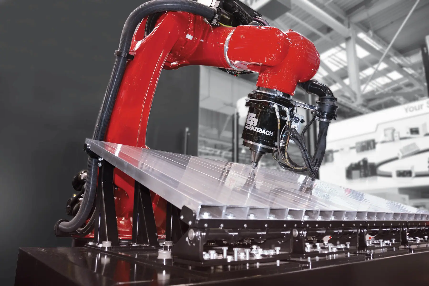 Kırmızı endüstriyel robot kolunun alüminyum profiller üzerinde sürtünme karıştırma kaynağı yaptığı üretim hücresi