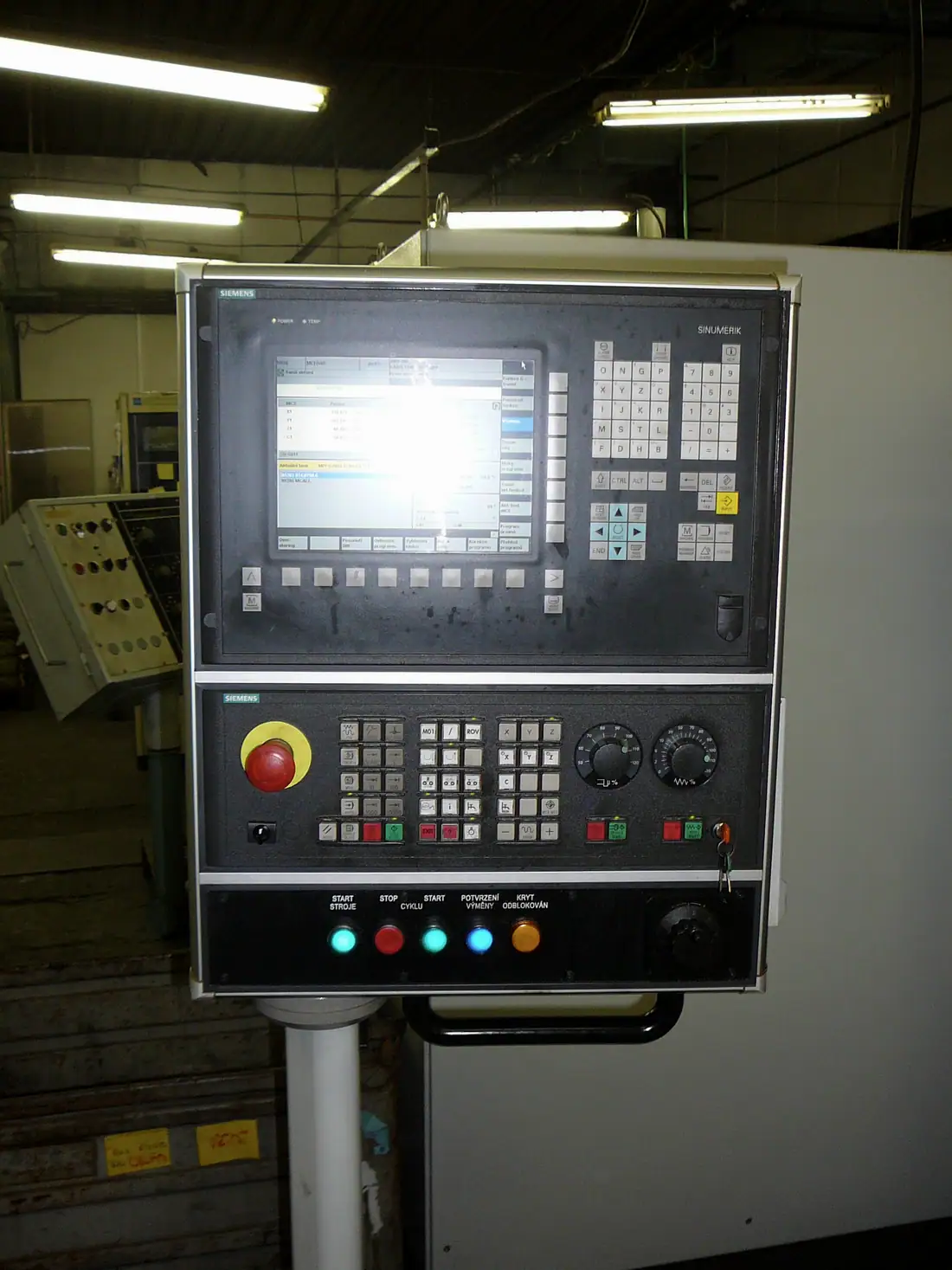 Eski bir CNC tezgâhının tuş takımlı kontrol paneli ve acil durdurma butonu