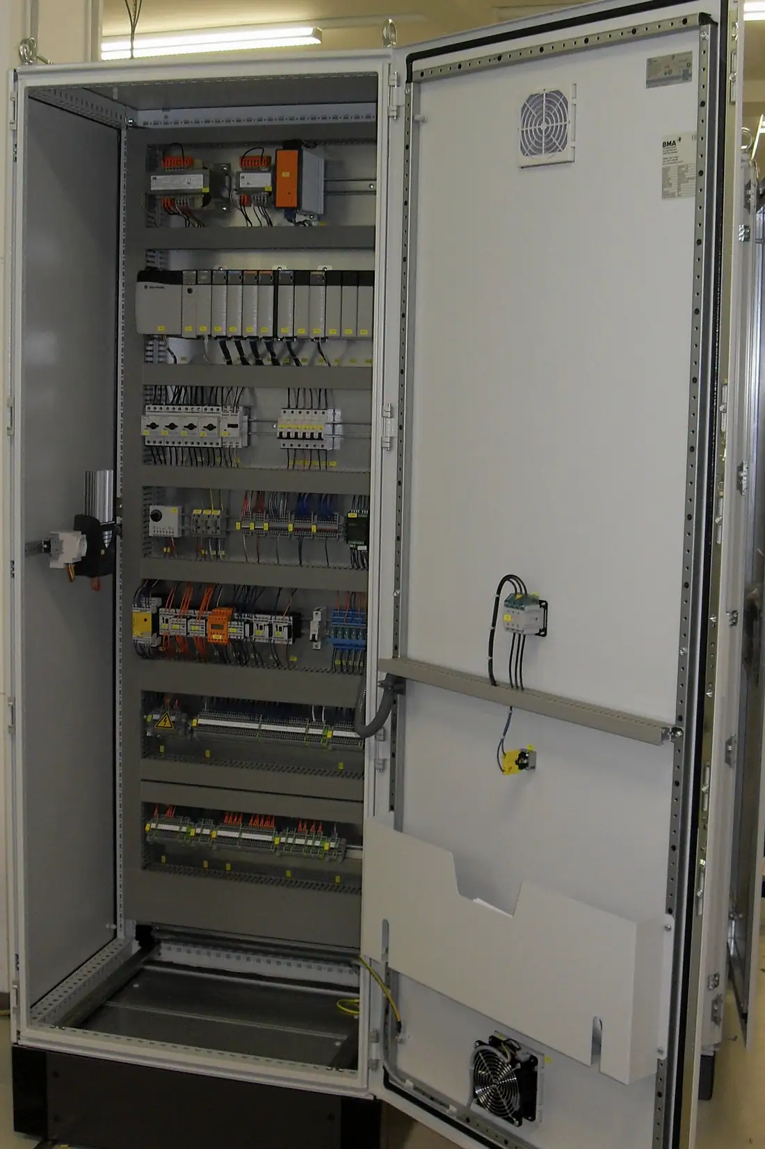 Açık elektrik panosunda PLC modülleri, sigortalar ve kablo kanalları